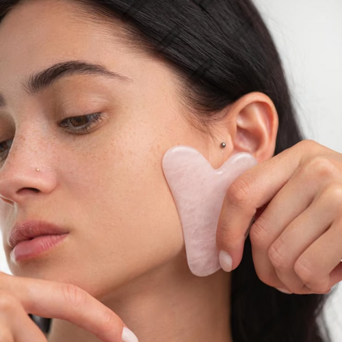 Femme utilisant un Gua Sha en quartz rose Ma boutique pour un massage facial relaxant