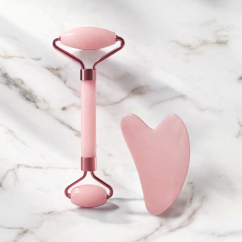 Set de massage Ma boutique composé d'un rouleau visage en quartz rose et d'une pierre Gua Sha sur fond marbré