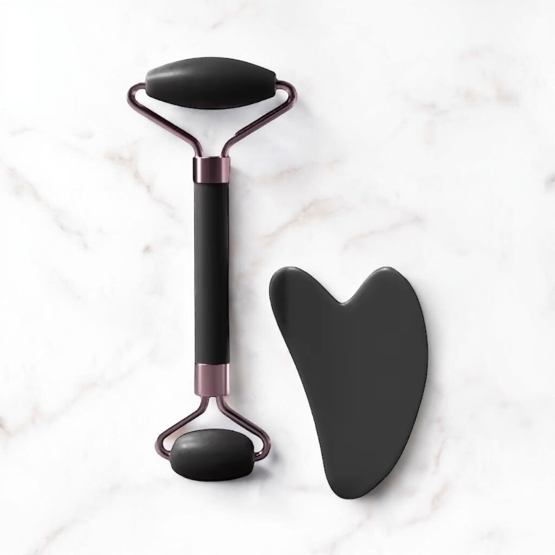 Ensemble Ma boutique de rouleau de massage facial et pierre Gua Sha en pierre noire sur fond de marbre blanc