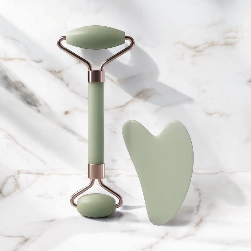 Ensemble Ma boutique de rouleau de massage pour le visage et pierre Gua Sha en pierre verte sur fond de marbre