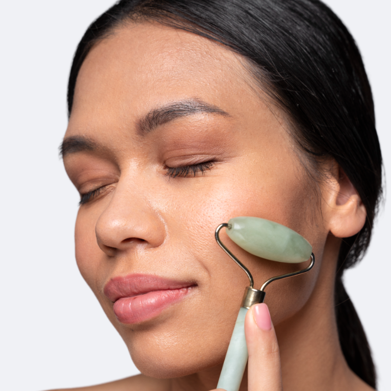 Femme utilisant un rouleau de massage facial en jade vert de la marque Ma boutique pour le soin de la peau